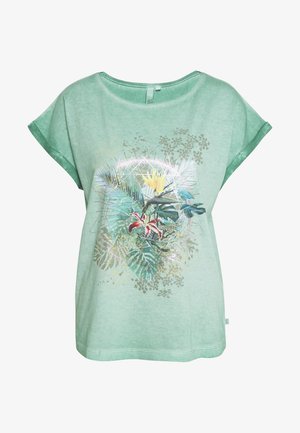 Lysegrøn T-shirt med korte ærmer med et tropisk blomsterprint med palmeblade, en gul og en rød blomst samt subtile gyldne detaljer.