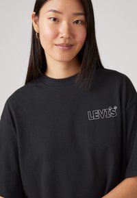 T-shirt en coton noir avec un logo Levi's brodé en blanc sur la poitrine gauche, à manches courtes et à coupe décontractée.