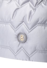 Grå dynejakke med chevron-vatteret design, der har en rund logoknap med et guld "B" på en grå baggrund.