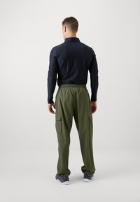 Marinblus med lång ärm och krage, kombinerad med olivgröna cargobyxor med sidofickor och lös passform, bärs med grå sneakers.