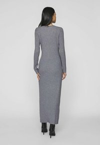 Long, form-fitting, gray ribbed dress with long sleeves, round neck, and a mid-calf hemline, paired with black heeled boots.