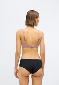 Podprsenka z jemného mauve materiálu s nastaviteľnými ramienkami a zapínaním na háčiky, doplnená čiernymi bezšvovými nohavičkami, ktoré predstavujú hladký dizajn.