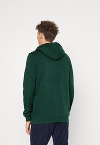 Felpa con cappuccio di un verde scuro, con un cappuccio regolabile e polsini e orlo a coste. Realizzata in un morbido tessuto testurizzato, presenta un design semplice.