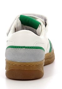 Zapatilla blanca con detalles verdes y talón de ante gris. Suela de goma con agarre texturizado, correa ajustable y collar acolchado para mayor comodidad.