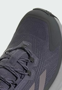 Baskets de sport grises dotées d'un upper en mesh respirant, d'un capuchon renforcé, d'accents texturés et d'une semelle rembourrée avec un logo discret.