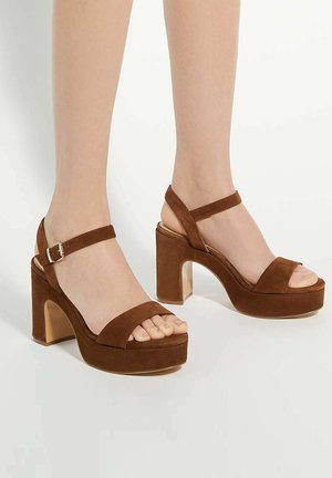 Sandales à plateforme en suède marron avec un talon épais, bout ouvert, bride de cheville réglable et finition lisse.