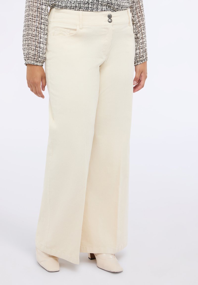 Pantaloni cream a gamba larga realizzati in tessuto morbido, dotati di due tasche anteriori, chiusura con zip e due bottoni, e cuciture minime.