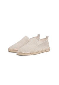 Scarpe slip-on in tela color beige con una superficie texturizzata, suola in juta intrecciata e un piccolo tab sul tallone per facilitarne l'indossamento.