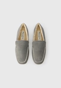 Pair of gray suede slip-on slippers with white stitching and soft beige fleece lining, branded Marc O’Polo inside.