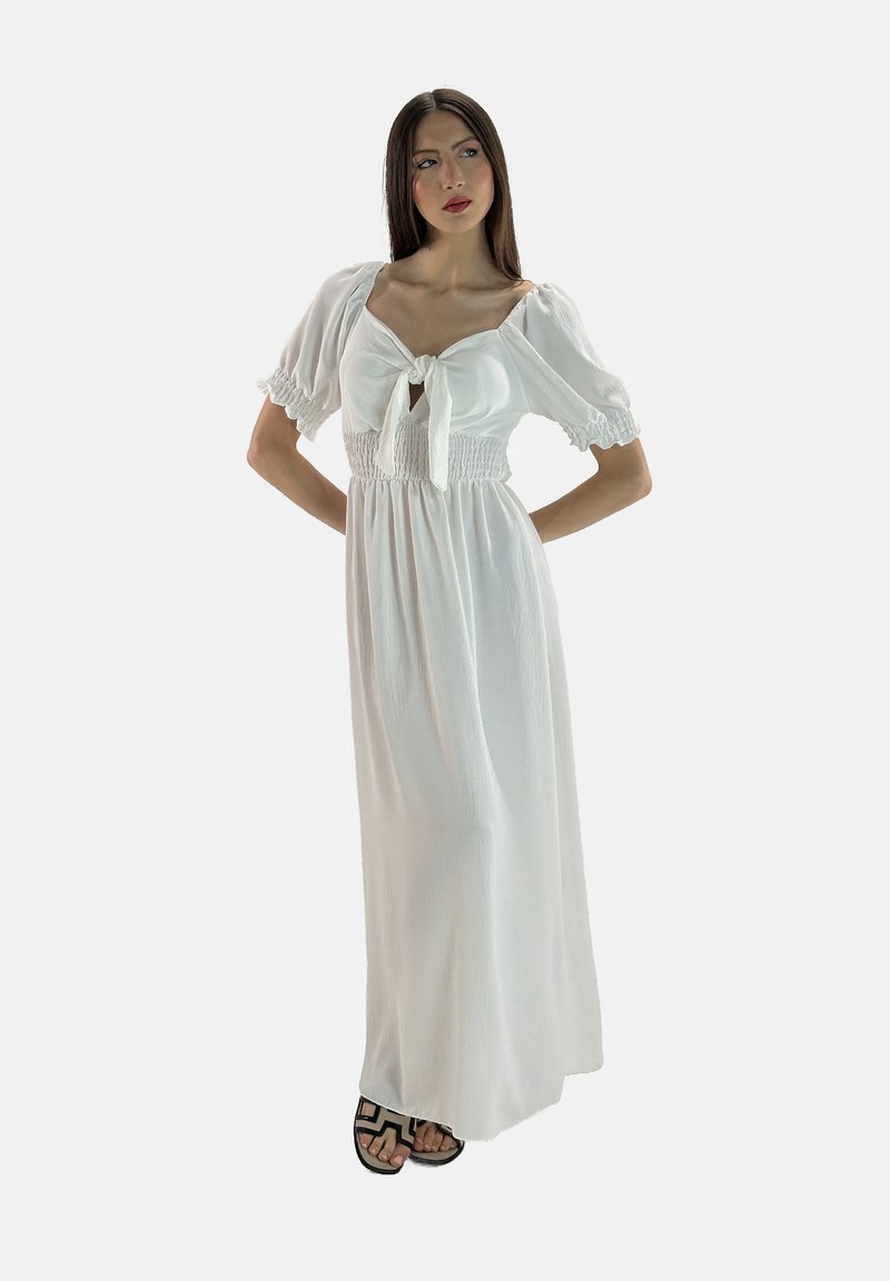 Abito maxi bianco con maniche a palloncino e dettaglio con nodo frontale. Presenta una vita arricciata e un tessuto leggero, offrendo una silhouette fluida.
