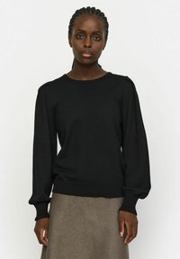 Maglione nero lavorato a maglia con maniche lunghe, polsini e corpo a coste; presenta un semplice scollo a girocollo e un leggero dettaglio a sbuffo sulle spalle.
