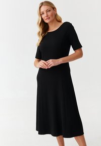 Musta midi-mekko lyhyillä hihoilla, pyöreällä kaula-aukolla, sileällä kankaalla ja istuvalla yläosalla, joka levenee kevyesti helmassa.