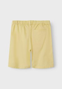 Gula bomullsshorts med elastisk midja, ovanför knä-längd och en enda bakficka. Slät textur och enkel design.