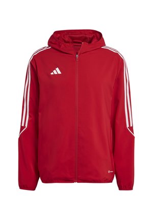 Czerwona kurtka z kapturem zapinana na zamek na całej długości, z białym logo Adidas na piersi oraz trzema białymi paskami biegnącymi wzdłuż każdego rękawa.
