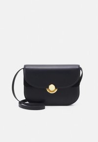 Melna ādas plecu soma ar noapaļotu pārsegu, zelta apaļu metāla rotājumu un noņemamu siksnu. Gluda tekstūra ar minimāliem akcentiem.