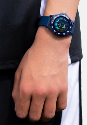 Orologio digitale con cinturino in silicone blu scuro e quadrante rotondo. Presenta un display retroilluminato che mostra numeri e accenti circolari.