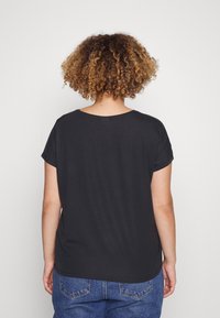 T-shirt nero a maniche corte con scollo curvo e vestibilità rilassata, realizzato in materiale morbido. Il retro presenta una texture liscia con un design semplice.