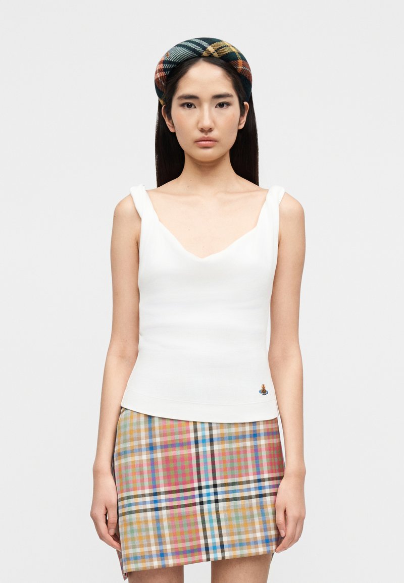 Λευκή πλεκτή μπλούζα-τοπάκι με φαρ διές τιράντες και λαιμόκοψη σε σχήμα V· συνδυάζεται με μίνι καρό φούστα σε διάφορες παστέλ αποχρώσεις και μαύρες λεπτομέρειες.