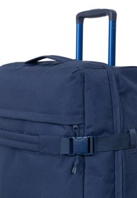 Bolsa de lona enrollable de tela azul marino con asa superior, correa ajustable y cierre de hebilla. Textura suave, forma rectangular y diseño robusto.