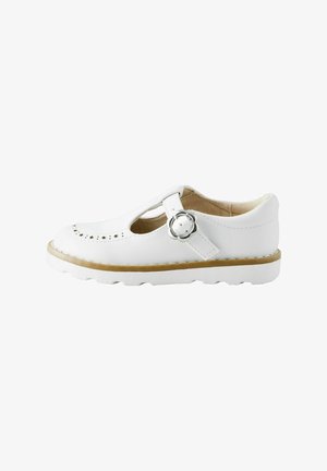 White leather shoe featuring a T-bar design, perforated star pattern, flower-shaped buckle, and a sturdy rubber sole with a contrasting edge.