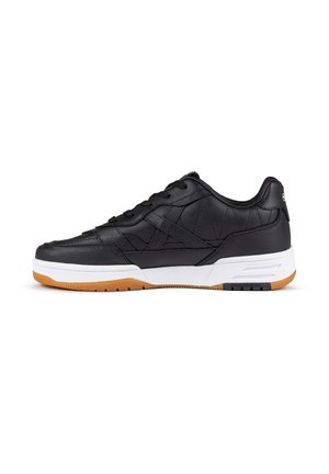 Zapatilla negra de cuero con detalles acolchados, media suela blanca y suela de goma color caramelo. Cuenta con cordones redondos y un collar acolchado para mayor comodidad.