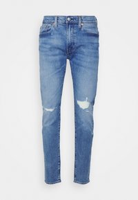 Ljust blå denimjeans med smal passform, med förstörda hål vid knäna och standard femfickdesign med metalldetaljer.