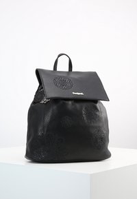 Schwarzer Leder-Rucksack mit umklappbarem Deckel, texturiertem Finish, floral geprägten Mustern und einem oberen Griff. Verstellbare Schulterriemen sind enthalten.