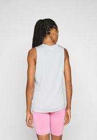 Lys grå ermeløs topp laget av myk stoff, kombinert med rosa fukttransporterende shorts. Har rund hals og diskret logo på baksiden.