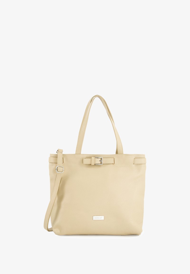 Beige læder tote bag med to skulderremme, en aftagelig crossbody-rem og en spændeaccent foran. Glat tekstur, minimalistisk design.