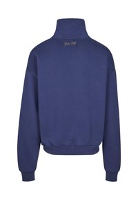 Felpa blu navy con colletto alto, polsini e vita a coste. Presenta un logo dorato sul retro. Tessuto morbido con vestibilità rilassata.