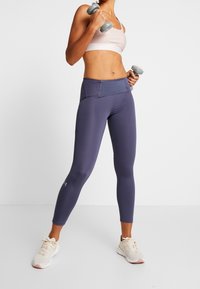 Light purple sports bra and dark purple leggings, made from smooth, elastic material. Leggings feature a high waistband and pockets.