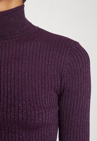 Fialový žebrovaný rolák z texturované látky s jemnými třpytivými akcenty a přiléhavým střihem.