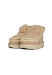 Zapatos de ante beige sin cordones con una textura suave, costuras decorativas a lo largo de los bordes y una suela gruesa de color claro.