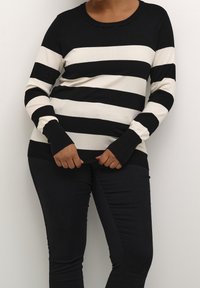 Pull en maille rayé noir et crème avec manches longues et encolure ronde. Tissu texturé avec poignets et ourlet côtelés.