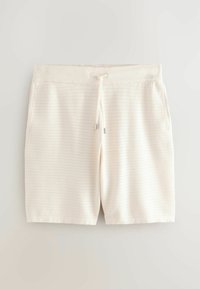 Shorts en tricot couleur crème avec une ceinture côtelée et un cordon de serrage, présentant un motif perforé horizontal subtil et des poches latérales.