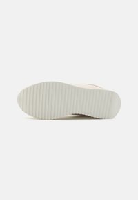 Suola di sneakers, gomma bianca con scanalature orizzontali. Design leggero, minimalista. Logo del marchio impresso nella zona del tallone.