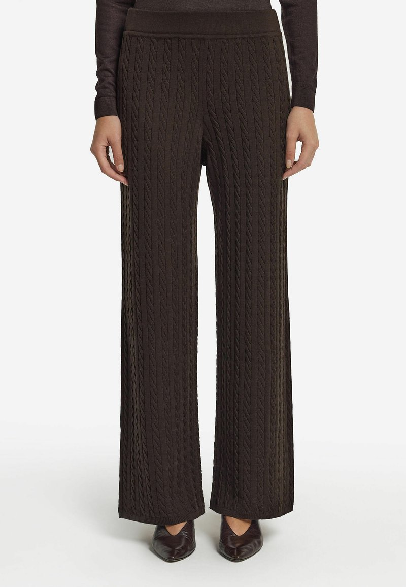 Szerokie, ciemno-brązowe, dzianinowe spodnie z teksturowanym splotem warkoczowym, z grubym pasem i luźnym krojem, zestawione z czółenkami.