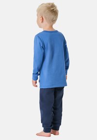 Hellblaues Langarmshirt mit rundem Halsausschnitt, kombiniert mit dunkelblauen Jogginghosen. Beide aus weichem Material, mit elastischen Bündchen an den Hosen.