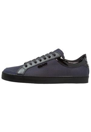 Low-top dark blue sneaker with black laces, black sole, and glossy black heel and trim details.