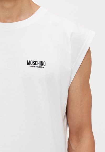 White sleeveless T-shirt made of cotton, featuring a black Moschino Underwear logo on the left chest area. Smooth texture.