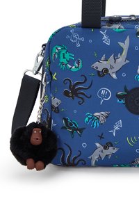 Borsa blu con motivo e grafica di vita marina, tra cui squali e polipi. Presenta un ciondolo nero testurizzato con una figura di scimmia attaccata.