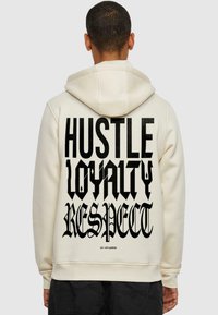 Cream hoodie featuring bold black text on the back: "HUSTLE LOYALTY RESPECT." Soft fabric, relaxed fit, with a drawstring hood.
