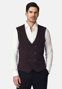 Bordowy wełniany kamizelka z dekoltem w kształcie V, zapinana na podwójne guziki, z dwoma bocznymi kieszeniami, noszona na białej koszuli.