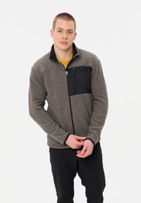 Gray textured jacket with a black front pocket and zipper, long sleeves, and a standing collar, paired with black pants.