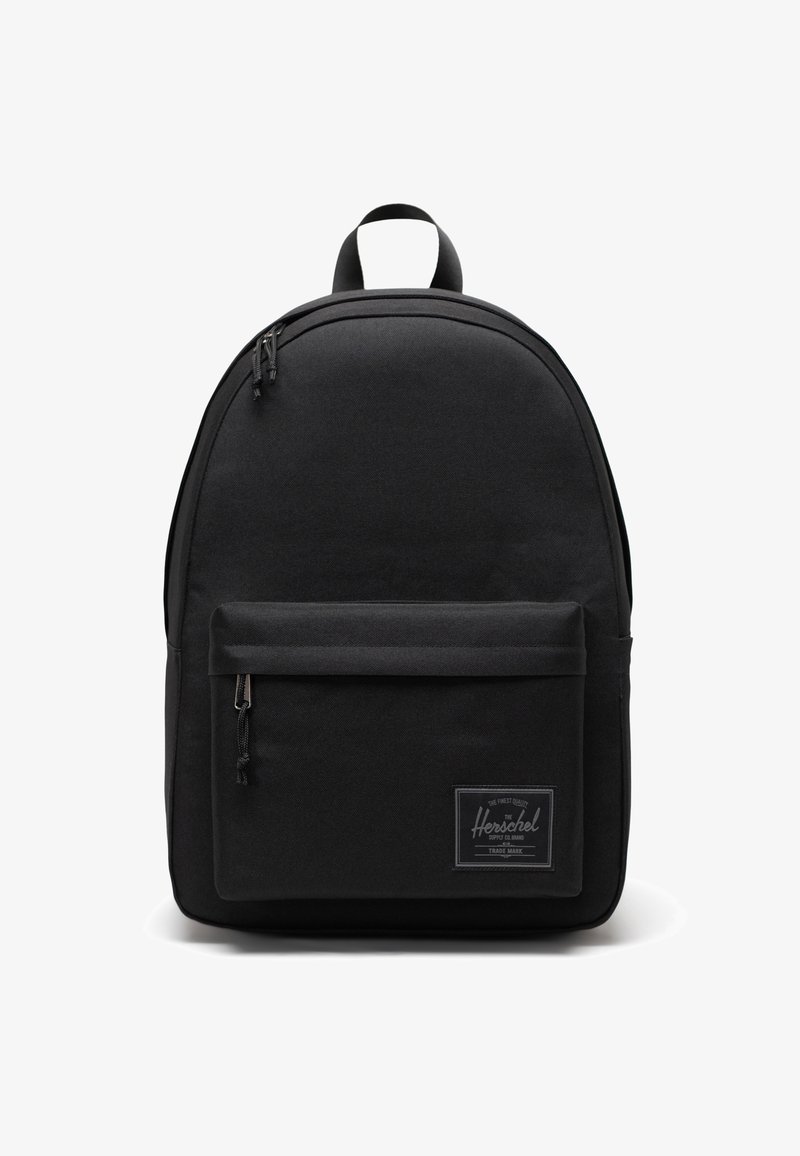 Czarna plecakowa torba z materiału o zaokrąglonym kształcie, przednią kieszenią, zamkami błyskawicznymi i naszywką z logo. Wykonana z trwałego materiału o minimalistycznym designie.
