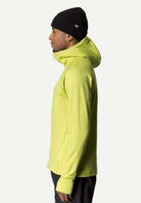 Lime green zip-up hoodie with a high collar and adjustable hood, featuring a side zip pocket and fitted cuffs. Black knit beanie worn.