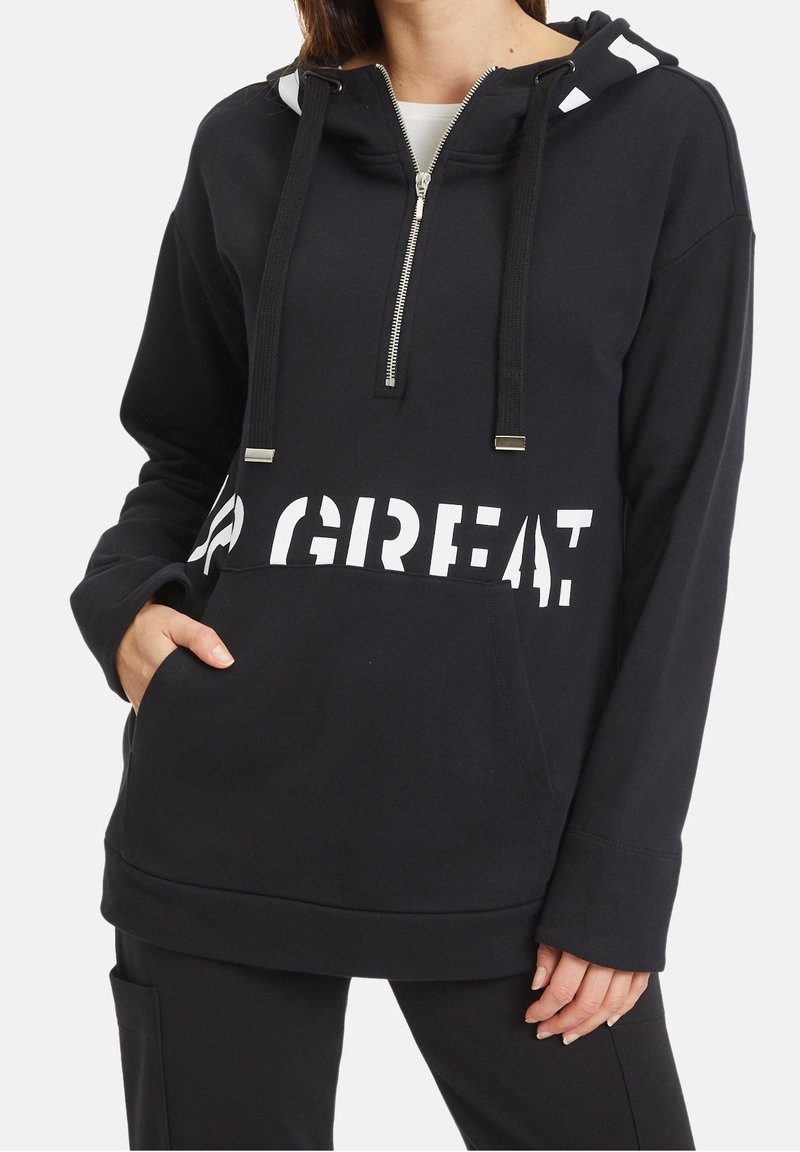 Hoodie noir avec col zippé, grande poche avant et texte blanc « GREAT. ». Offre une coupe confortable et une texture douce.