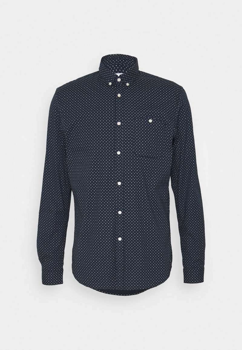 Námořnická modrá košile s dlouhým rukávem a bílým geometrickým vzorem, s klasickým límečkem, přední kapsou a zaobleným lemem.