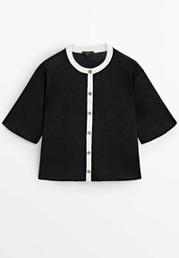 Chemise noire à manches courtes avec un col rond blanc, fermeture boutonnée à l'avant avec des boutons dorés, et une coupe décontractée.