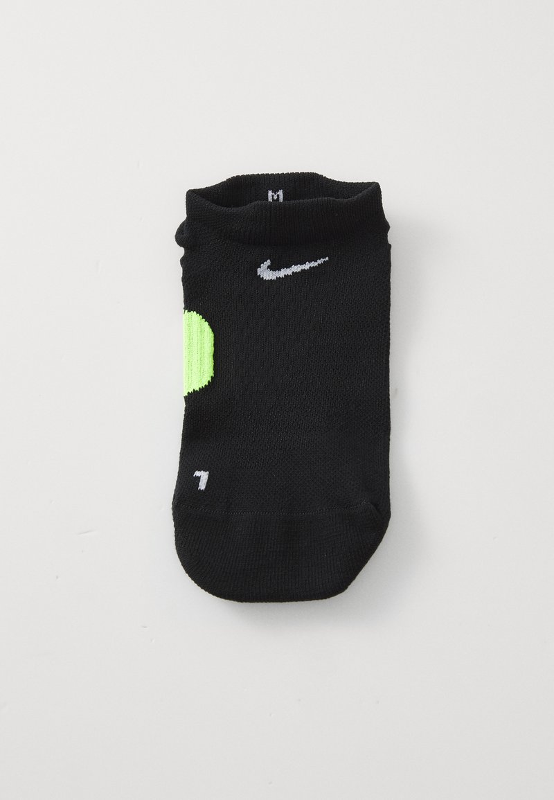 Schwarze Knöchelsocke mit weißem Nike-Swoosh, neongrünem Patch an der Ferse und "L"-Markierung an der Zehe, flach auf weißem Hintergrund gefaltet.